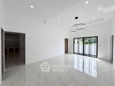 Spacious modern living room with elegant lighting and large windows offering natural light.