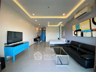 Spacious modern living room with sleek black leather sofa and large TV, open layout design.