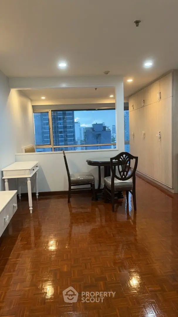 Spacious living room with polished wooden floors and city view, perfect for urban living.