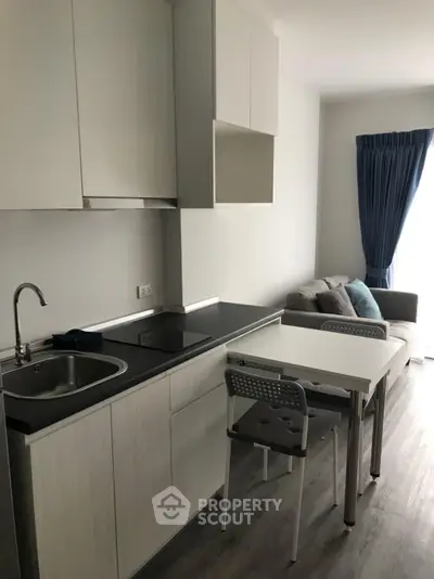 Modern compact kitchen with sleek cabinetry and cozy living area in stylish apartment.