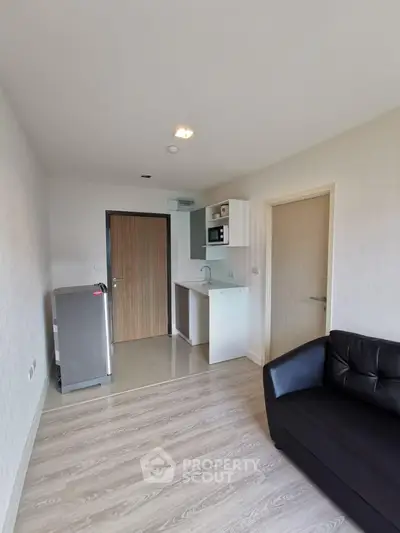 Modern apartment interior with compact kitchen and cozy living area, featuring sleek flooring and minimalist design.