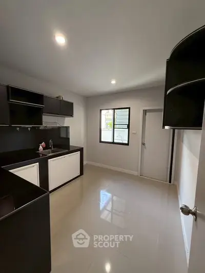 Modern kitchen with sleek black cabinets and glossy floor tiles