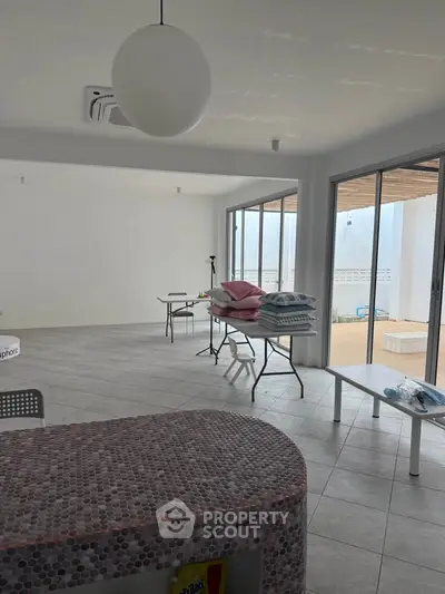 Spacious open-plan living area with large windows and modern tiled flooring.