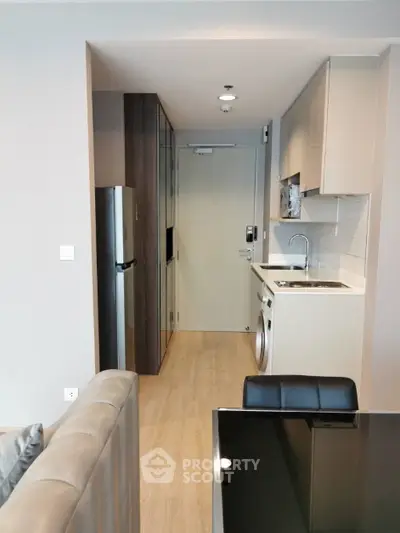 Modern compact kitchen with integrated appliances and sleek cabinetry in a stylish apartment.
