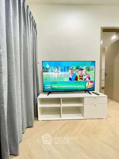 Modern living room with TV and stylish white cabinet, featuring elegant curtains and wooden flooring.