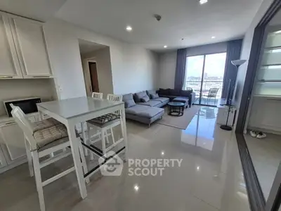 Modern living room with open layout and city view, featuring sleek furniture and bright lighting.