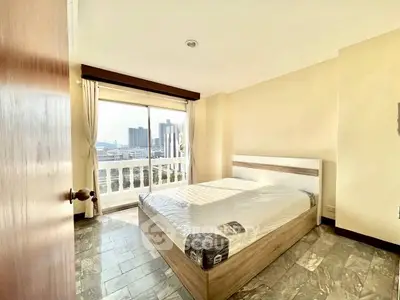 Bright bedroom with city view and large window, featuring a modern bed and natural light.