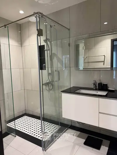 Modern bathroom with glass shower enclosure and sleek vanity in contemporary design.