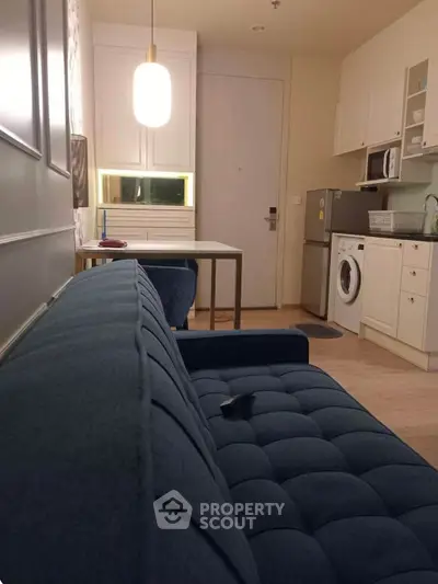 Chic modern apartment with cozy living area and compact kitchen featuring washing machine and microwave.