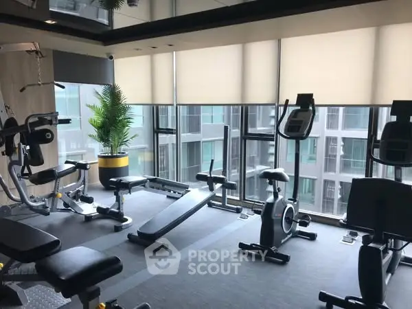 Modern gym with state-of-the-art equipment and large windows in a high-rise building.