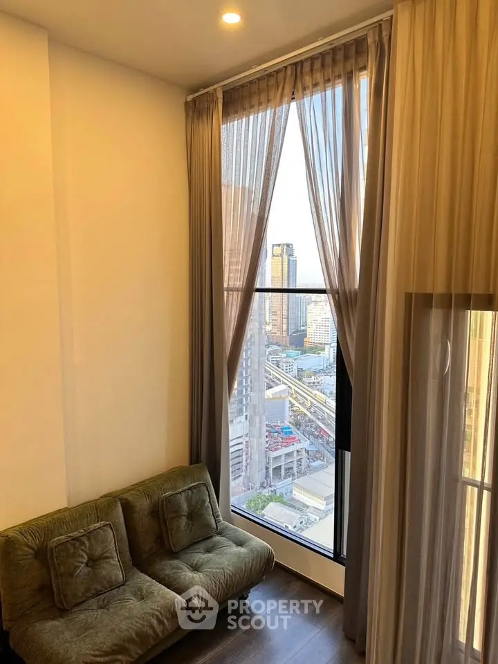 Stylish living room with floor-to-ceiling windows offering stunning city views, perfect for urban living.