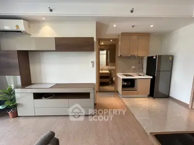 Modern open-plan living room with kitchen featuring sleek cabinetry and stainless steel appliances.