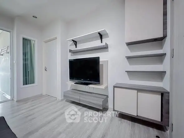 Modern living room with sleek TV unit and stylish shelving in a bright apartment.