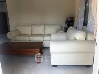 Cozy living room with elegant white sofas and wooden coffee table, perfect for relaxation.