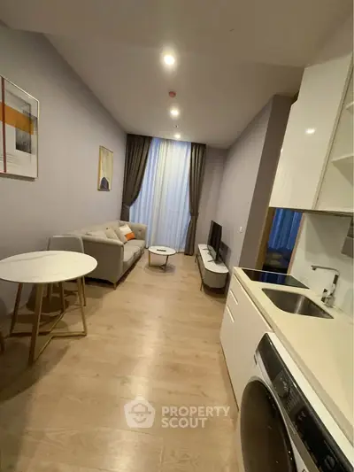 Modern living room with sleek furniture and integrated kitchen appliances in a cozy apartment.