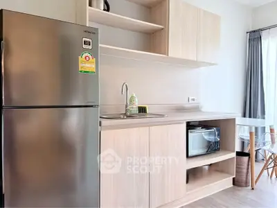 Modern kitchen with sleek cabinetry and stainless steel fridge in a bright apartment.