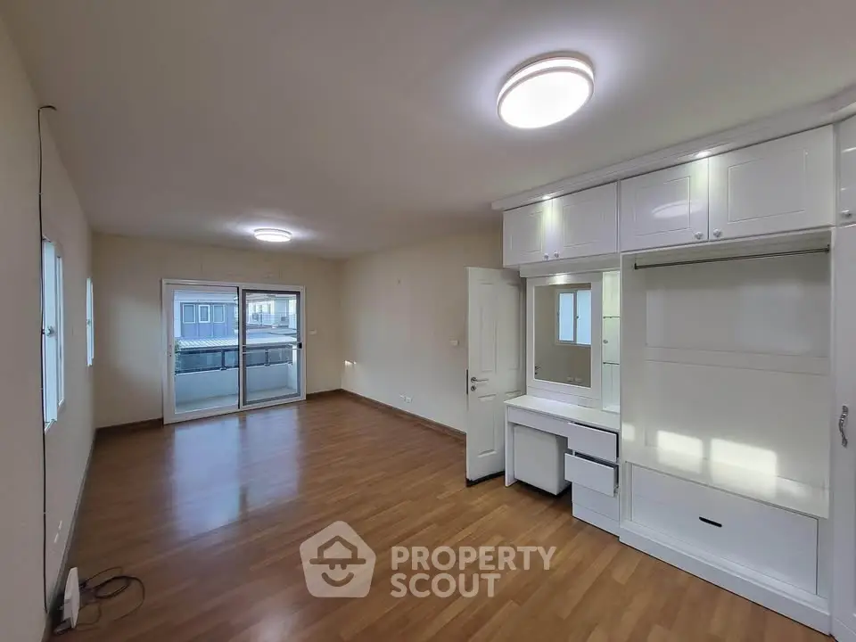 Spacious empty room with wooden flooring and built-in storage, ideal for customization.