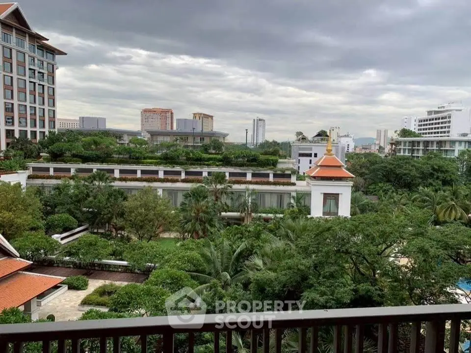 Stunning cityscape view from a balcony overlooking lush greenery and modern buildings.