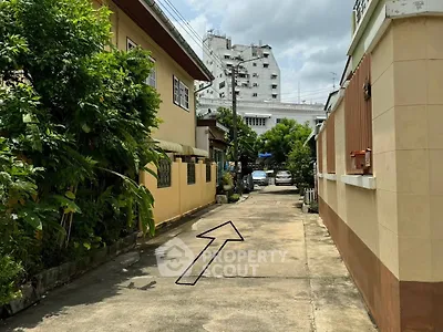 Charming residential alley with lush greenery and urban backdrop, perfect for serene living.