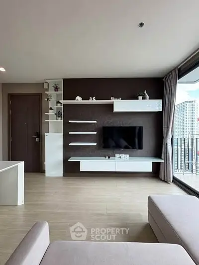 Modern living room with sleek TV unit and large windows offering city views