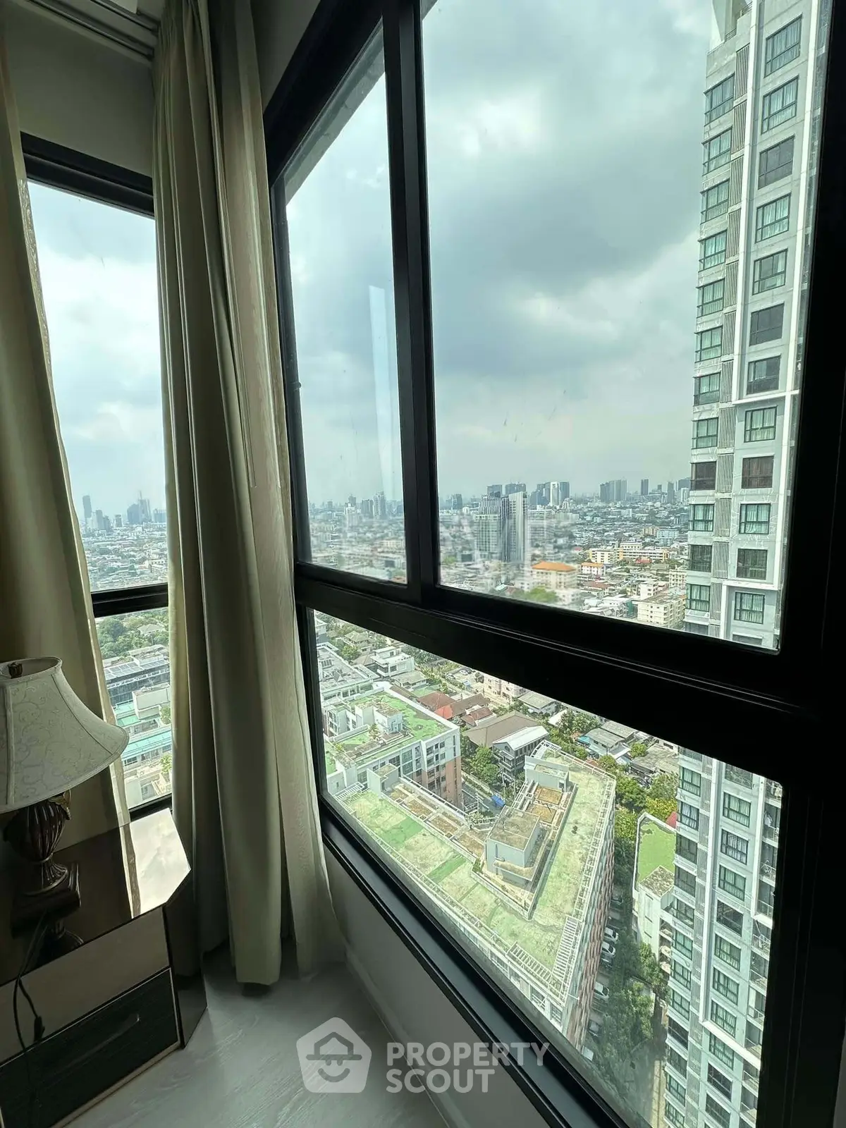 Stunning cityscape view from high-rise apartment window with modern decor and natural light.