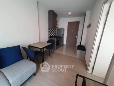 Modern apartment interior with compact kitchen and cozy living area, featuring stylish furniture and wood flooring.