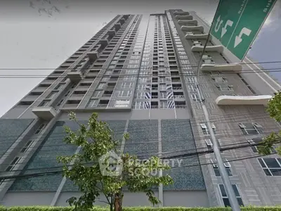 Modern high-rise building with sleek design and lush greenery at the base.