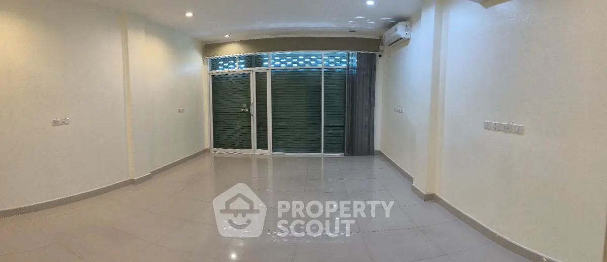 Spacious empty living room with large windows and tiled flooring, perfect for customization.