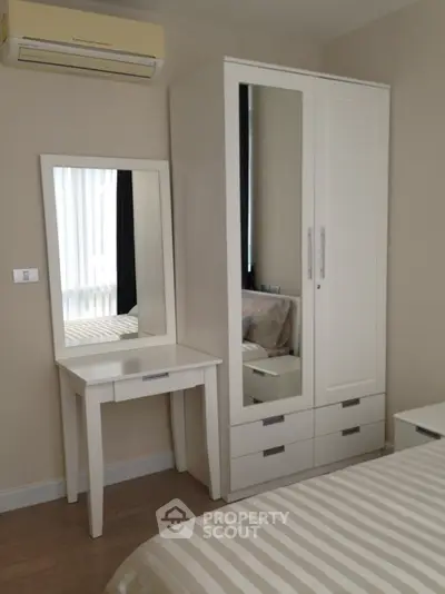 Modern bedroom with sleek white furniture and air conditioning unit, perfect for a cozy living space.