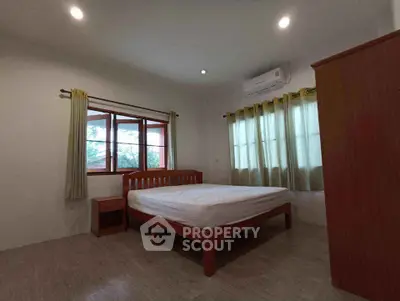 Spacious bedroom with wooden furniture and large windows for natural light.