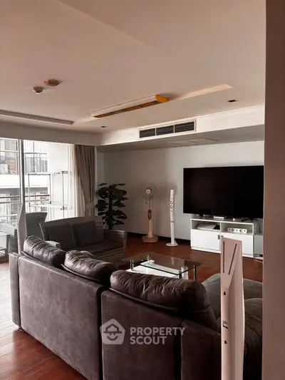 Spacious living room with modern decor and large TV, featuring comfortable seating and natural light.