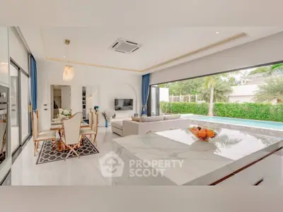 Luxurious open-plan living room with pool view and elegant marble kitchen island.