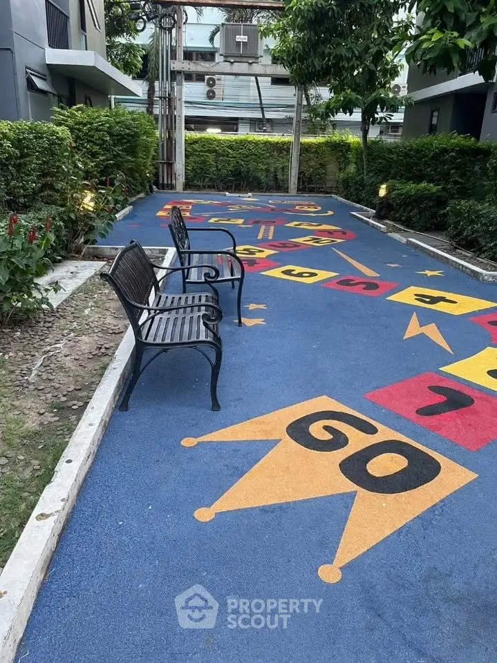 Charming outdoor play area with colorful hopscotch design and benches in a modern residential complex.