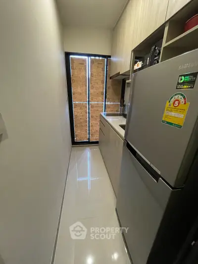 Modern compact kitchen with sleek cabinetry and stainless steel fridge, perfect for urban living.