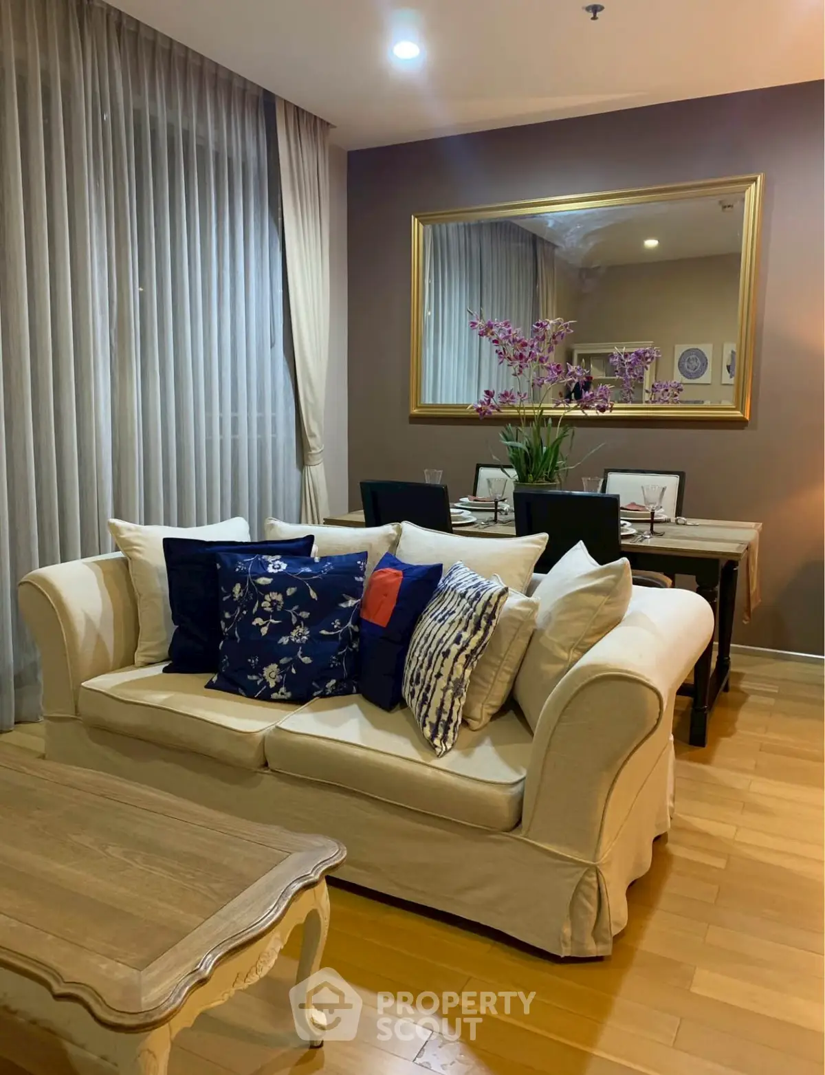 Elegant living room with cozy sofa and dining area, featuring stylish decor and warm lighting.