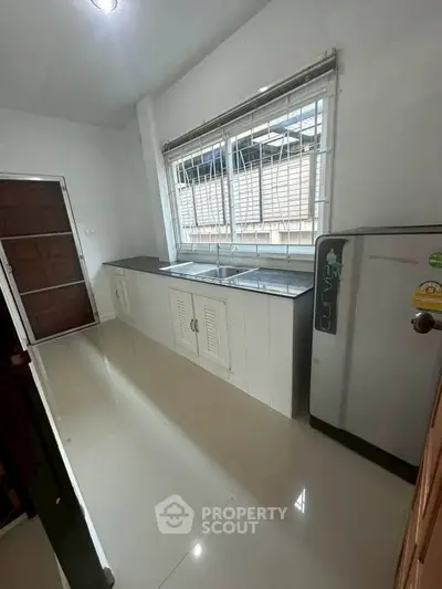 Spacious kitchen with modern appliances and large window for natural light.