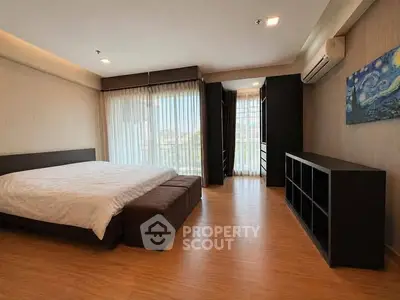 Spacious bedroom with large windows and modern furnishings in a luxury apartment.
