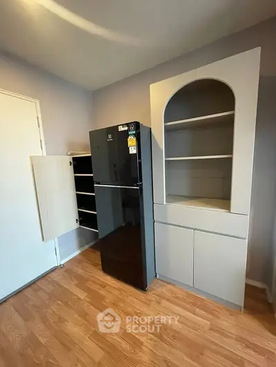 Modern kitchen with sleek black fridge and stylish cabinetry on wooden flooring.