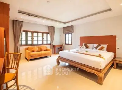 Spacious bedroom with elegant decor and natural light, featuring a cozy seating area and modern furnishings.