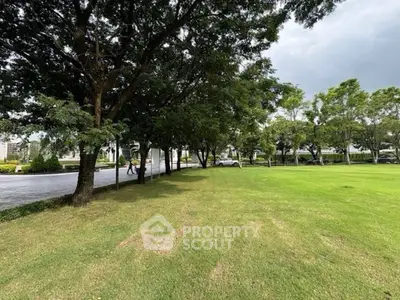 Spacious green garden area with lush trees and open lawn, perfect for relaxation.