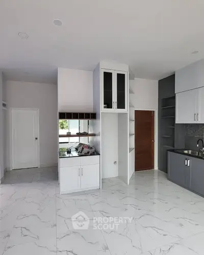 Modern kitchen with sleek cabinetry and marble flooring in a contemporary apartment.