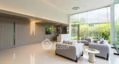 Luxurious modern living room with elegant sofas and large windows offering garden views.