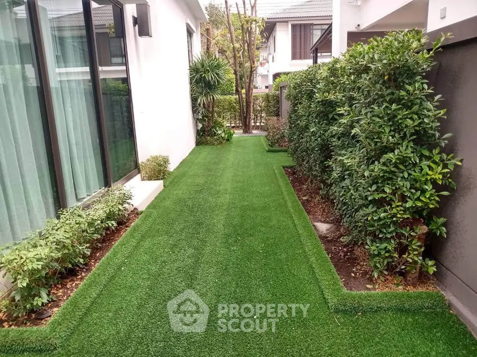 Charming garden pathway with lush greenery and modern house exterior.