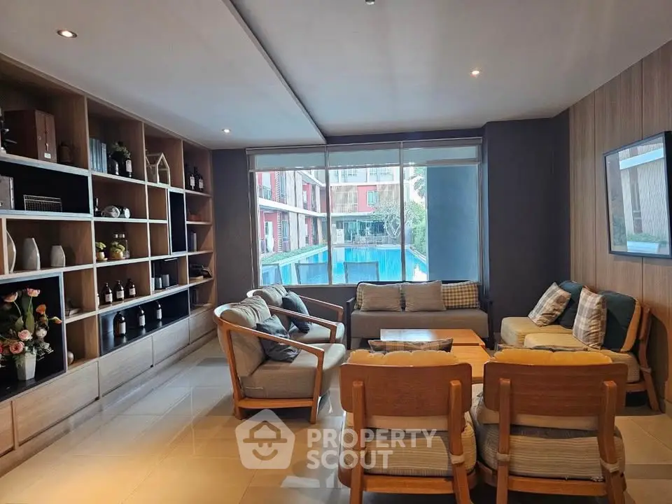 Spacious living room with pool view, elegant furniture, and built-in shelving in modern apartment.