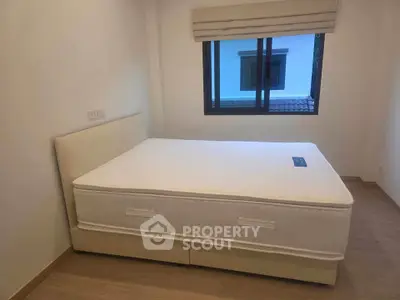 Cozy bedroom with a comfortable bed and large window offering natural light.