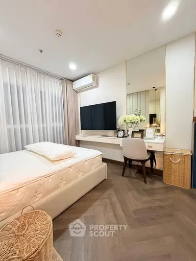 Modern bedroom with elegant decor, featuring a large TV and stylish vanity area.