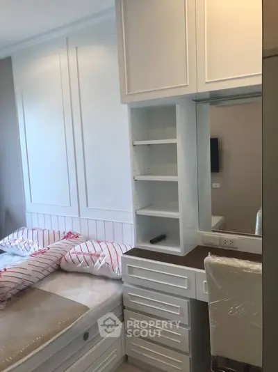 Modern bedroom with built-in storage and sleek white cabinetry.