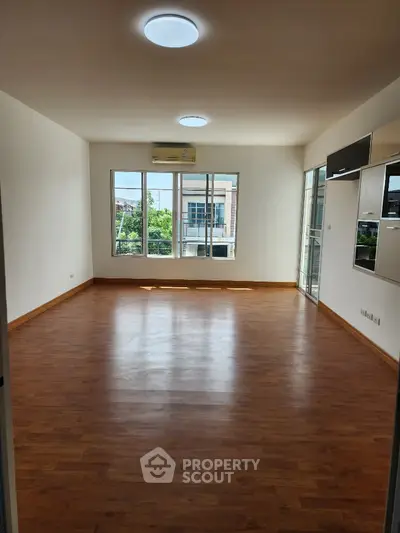 Spacious empty living room with wooden flooring and large windows