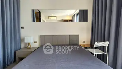 Modern bedroom with stylish decor and large mirror, featuring elegant curtains and contemporary furniture.