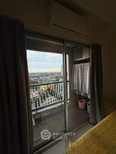 Cozy bedroom with balcony offering city view and air conditioning unit.